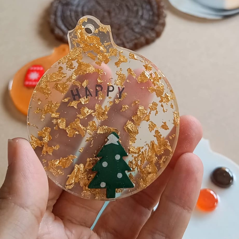 Adorno de Navidad hecho a mano con resina con árbol de navidad y mensaje Happy. Taller de decoración Navideña Siete Maderas.