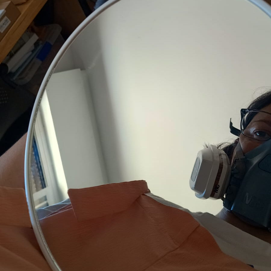 Creadora de siete maderas reflejada en un espejo para intervenir con resina y con la mascarilla de seguridad puesta.