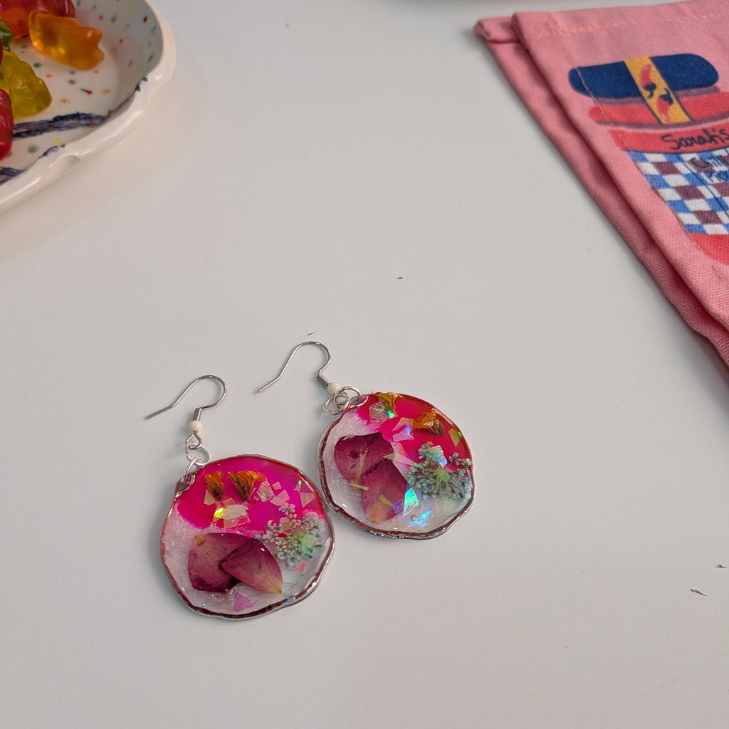 Pendientes realizados por una alumna con resina y flores naturales, aplicando pigmentos y encapsulados.