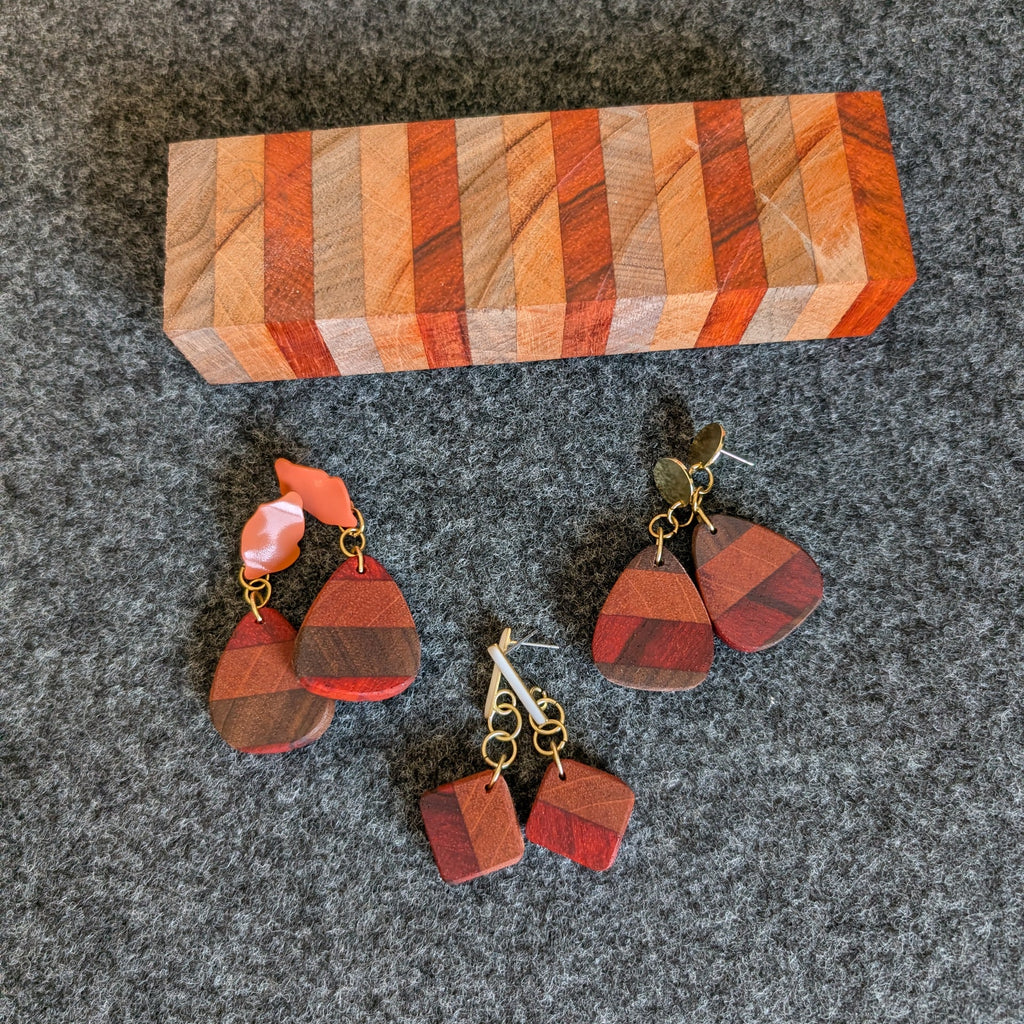 Pendientes de madera hechos a mano por Siete Maderas. Tres diseños únicos. Al lado el bloque de madera del que se obtuvieron. 
