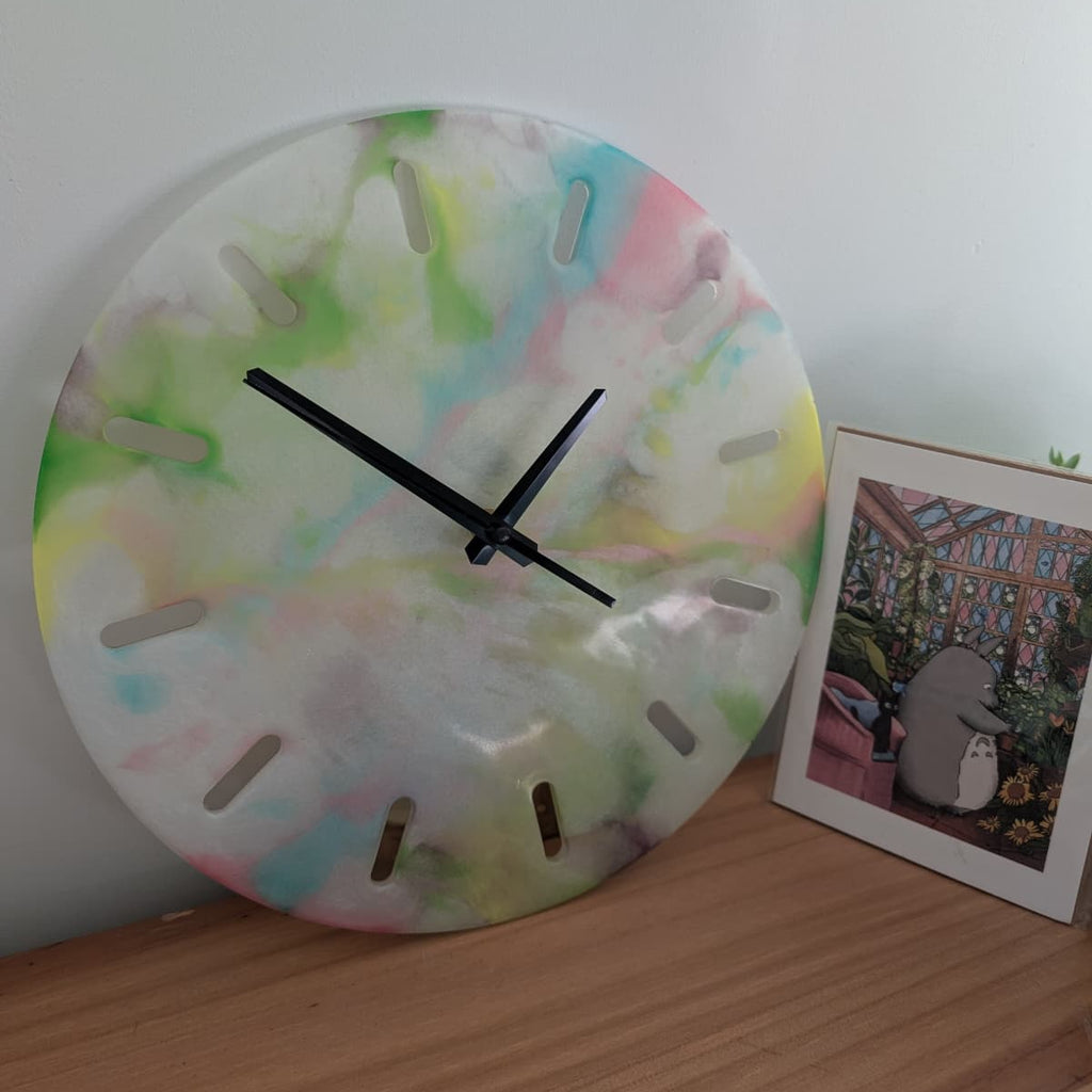 Reloj de resina hecho a mano por Siete Maderas. Fondo blanco nácar y multicolor. Diseño único.