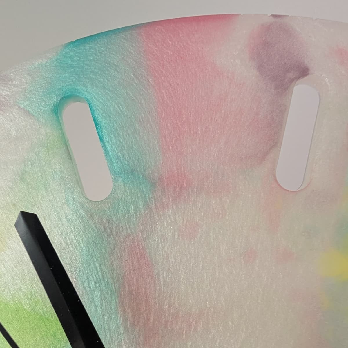 Reloj de resina hecho a mano por Siete Maderas. Fondo blanco nácar y multicolor. Diseño único. Detalle de los colores.