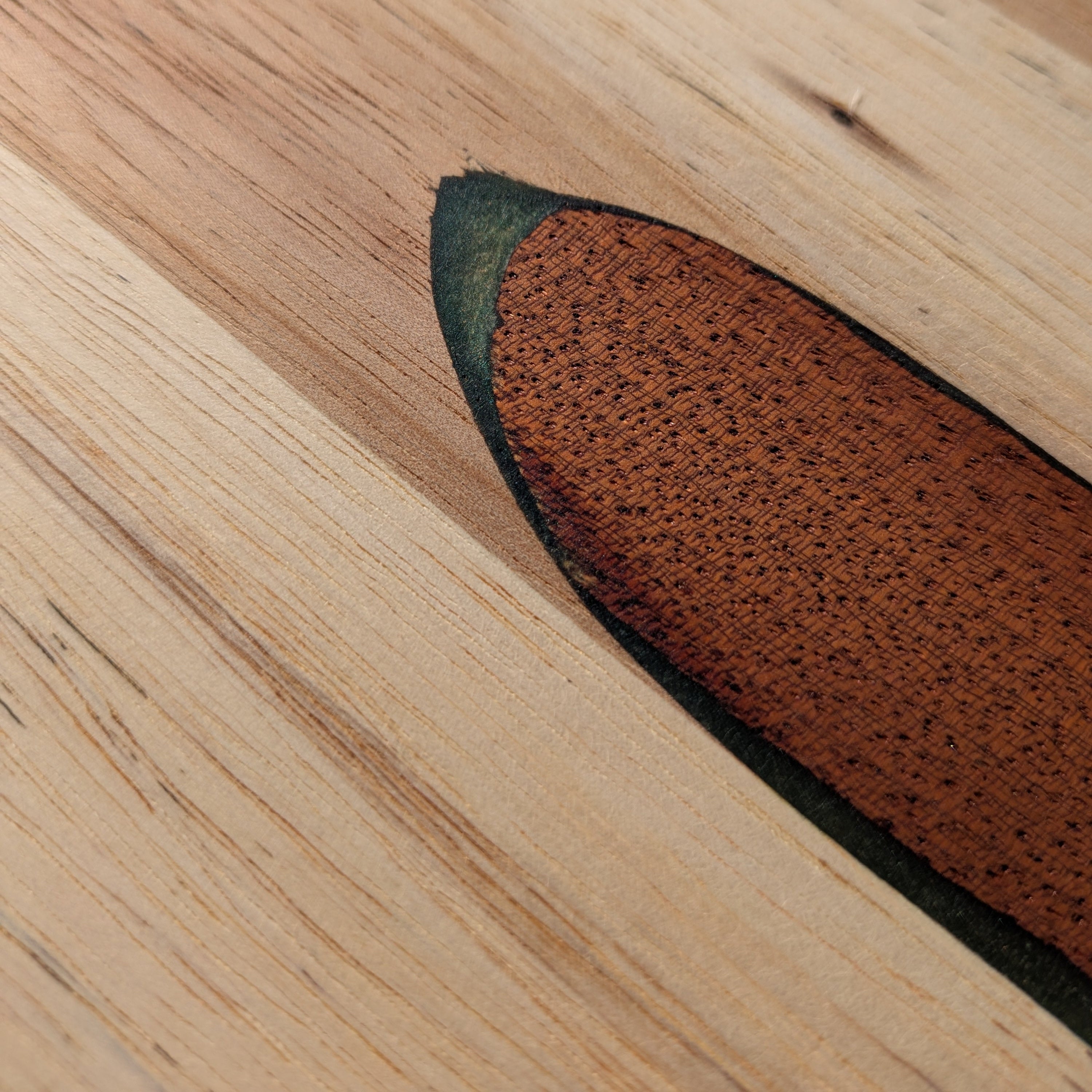 Tabla gourmet de madera noble hecha a mano con diseño de hoja. Artesanía de autor funcional por Siete Maderas, hecho en Málaga. Detalle de la resina verde.