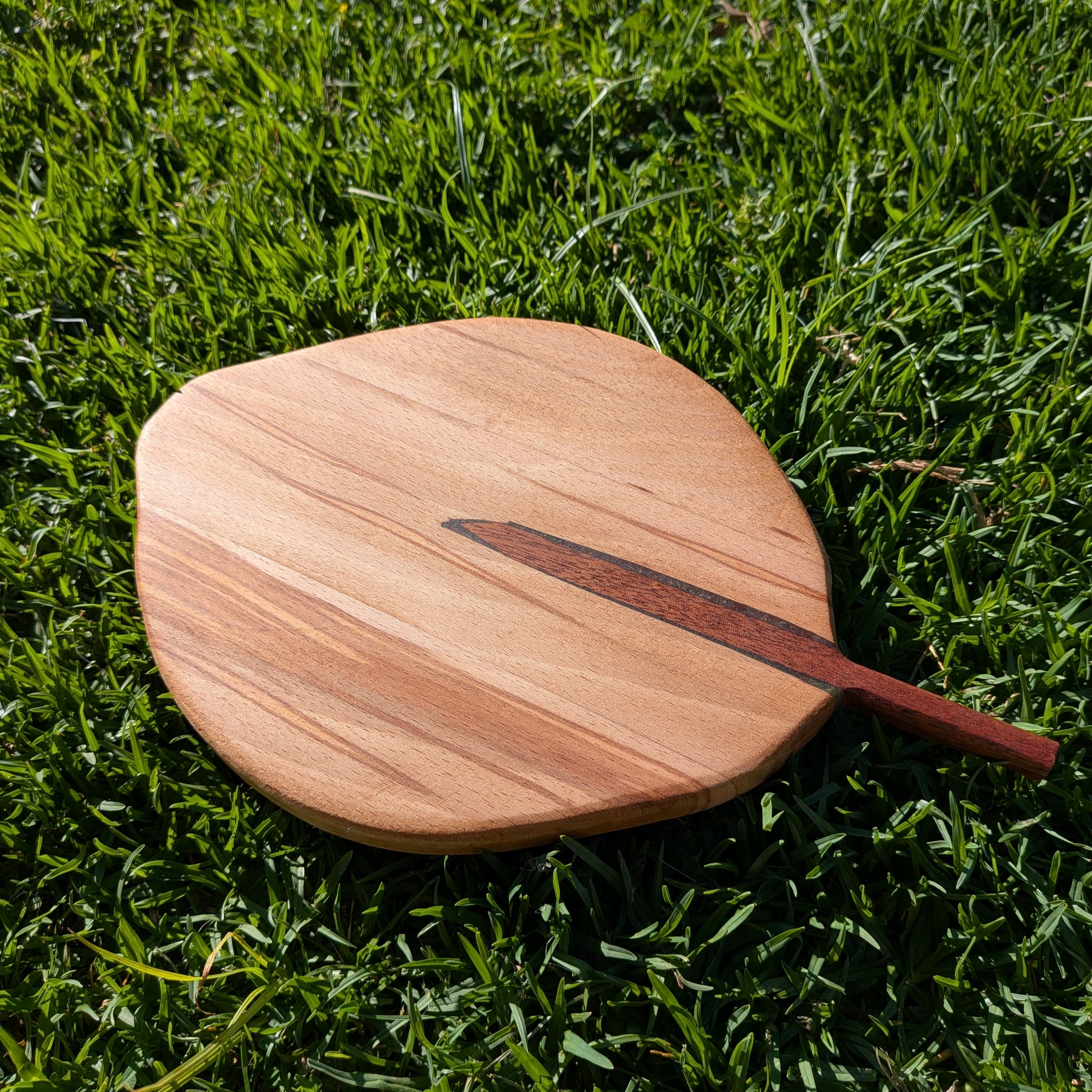 Tabla de servir con forma de hoja hecha a mano en dos maderas diferentes y un toque de resina verde. Hecho por Siete Maderas en su taller de Málaga.