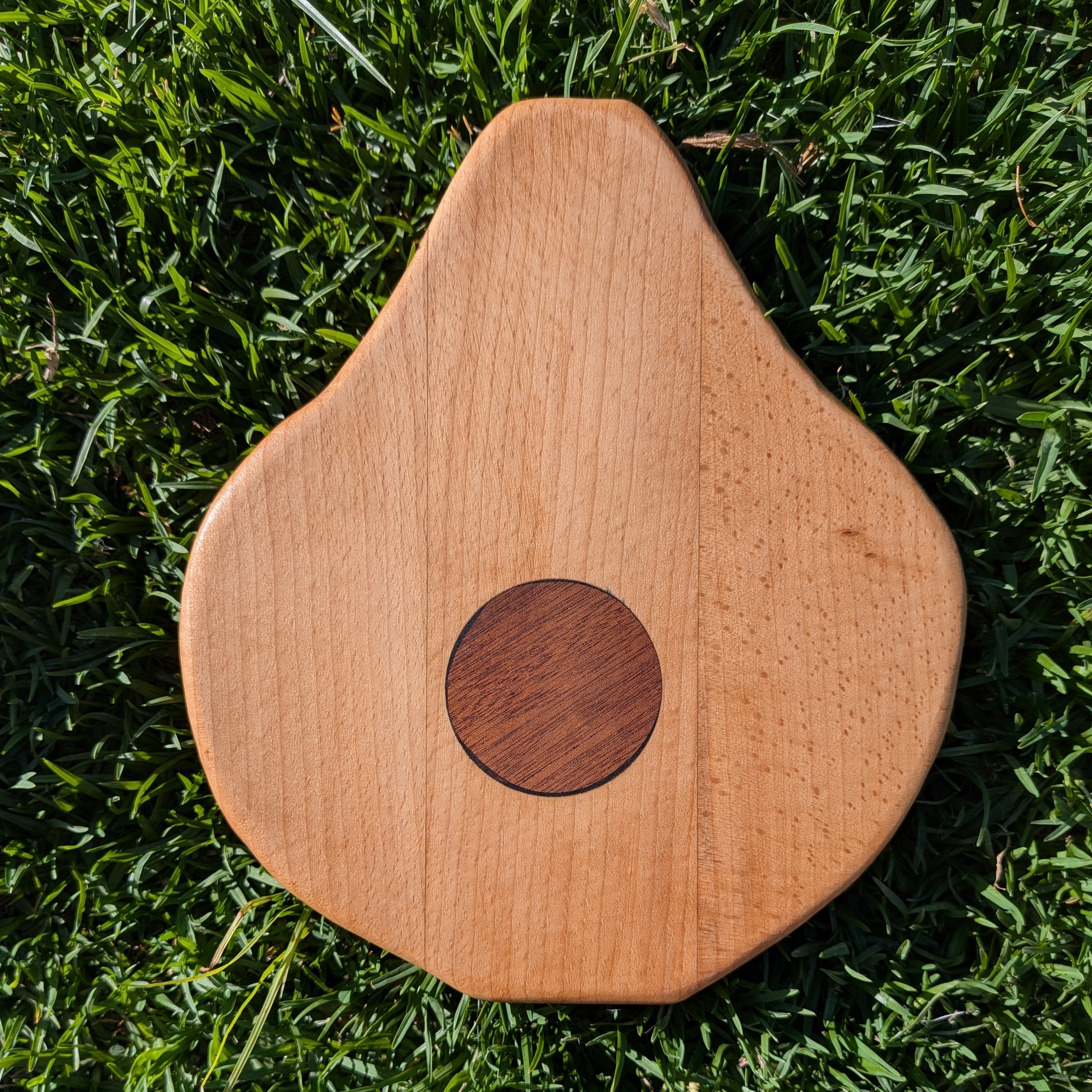 Tabla de servir con forma de aguacate, uso de dos maderas nobles y detalle de resina. Hecha a mano por Siete Maderas en su taller de Málaga.
