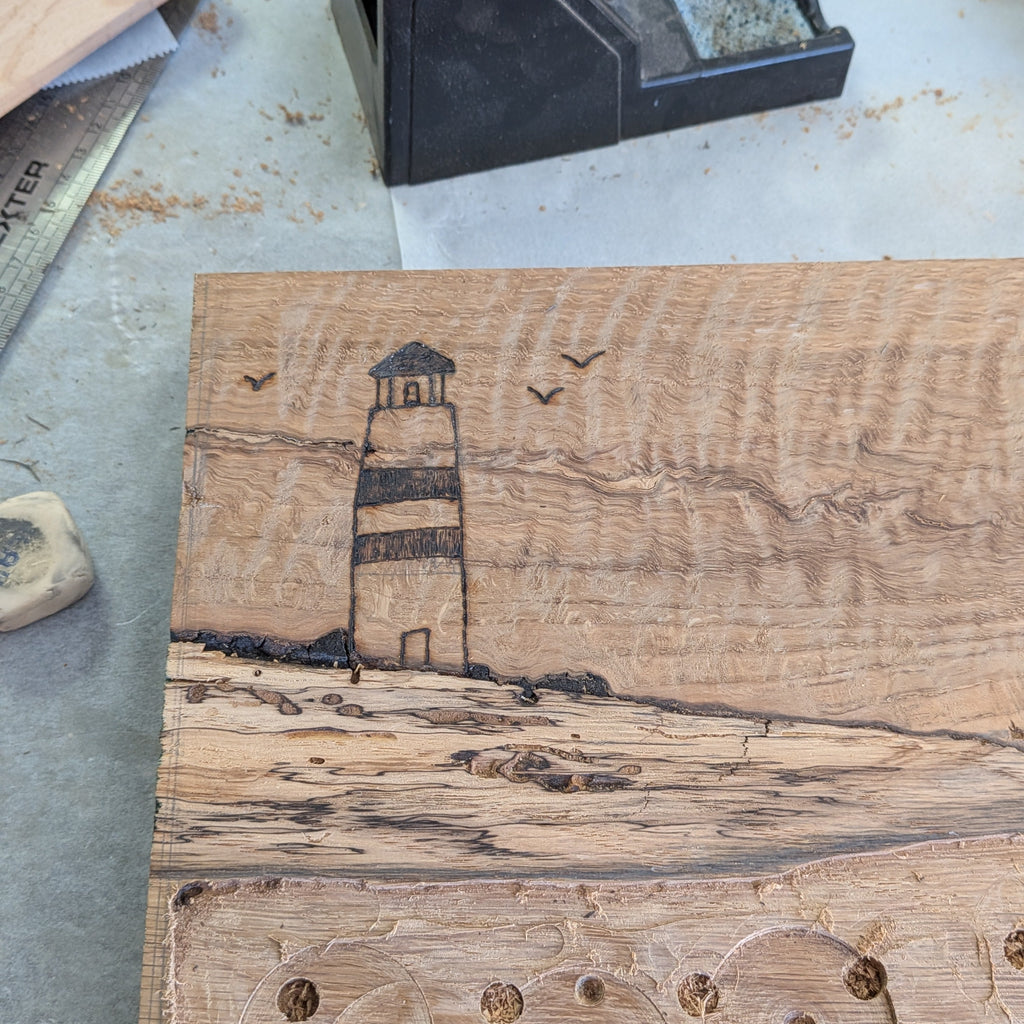 Tabla de servir El faro, hecha a mano por Siete Maderas en madera de roble, usando el nudo como parte del diseño y con detalles en resina simulando el mar y pirograbado dibujando un faro y unas gaviotas. Proceso creativo.