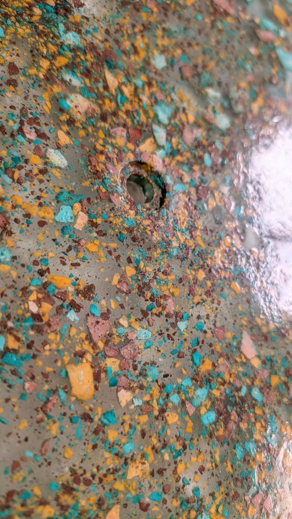 Detalle de la creación a mano del reloj grava hecho con resina ecológica simulando grava de colores en resina epoxy. Colores verde, mostaza y marrón. Siete Maderas