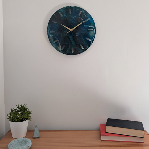 Reloj de pared redondo de resina Skuld, en tonos de azul oscuro y vetas blancas para dar un efecto de mar profundo. Es la decoración perfecta para una cómoda y realza cualquier espacio.