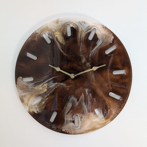Reloj de pared redondo Urd, con resina y serrín reciclado. Tonos tierra, vetas blancas y doradas, agujas doradas. Una pieza artesanal sostenible.