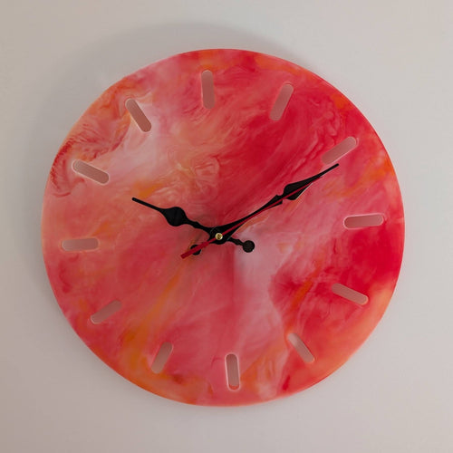 Reloj de resina artesanal Verdandi, una explosión de color para tu pared. Tonos frambuesa y naranja coral, con vetas blancas y agujas negras. Decoración única.