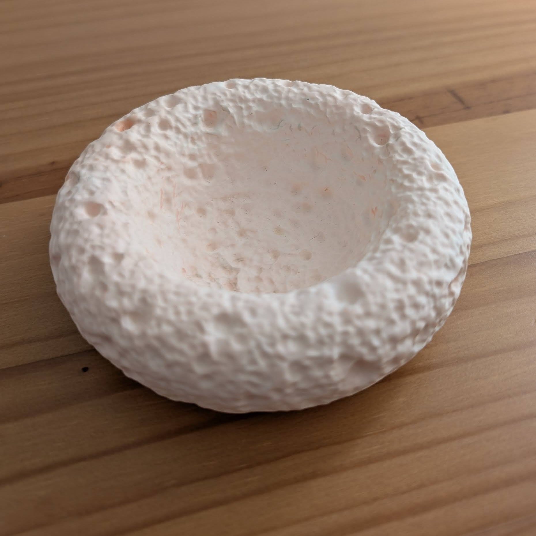 El detalle del vaciabolsillos Calma. Resina al agua en tonos coral y salmón. La delicada textura que simula una piedra porosa.