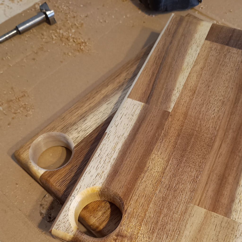 Tabla de cortar y servir Cima. Una pieza versátil de madera de acacia. Su agujero superior te permite colgarla, dándole un toque decorativo.