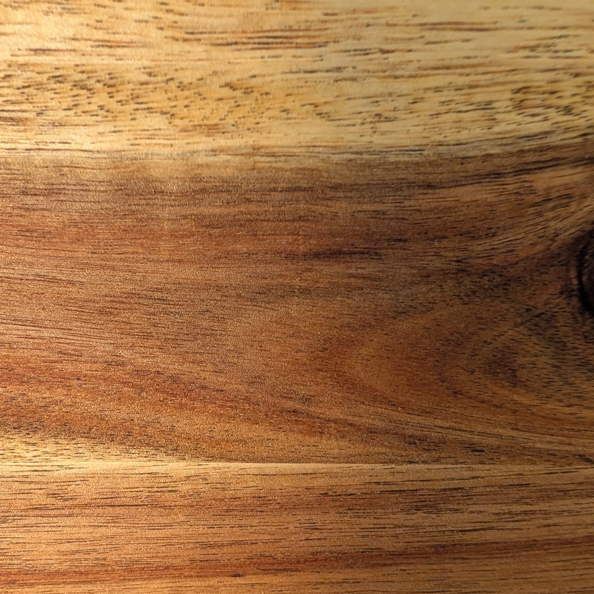 Primer plano mostrando las vetas únicas de la madera de acacia. La calidad y el trabajo artesanal en cada detalle.