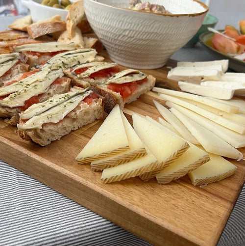 La tabla Sierra de Siete Maderas, ideal para servir quesos y aperitivos. Su madera de acacia artesanal realza tu mesa. ¡Momentos especiales en tu hogar!